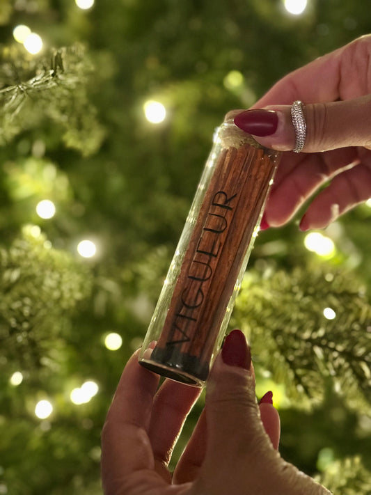 Person holding a glass vial filled with matches labeled 'Vigueur'